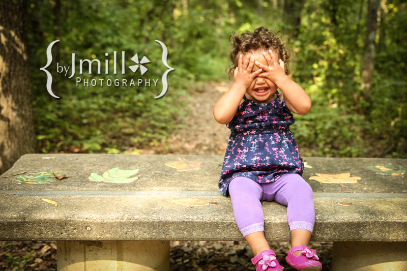 baby girl playing peek a boo on bench