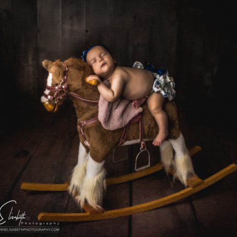 Newborn Baby Girl on Rocking Horse