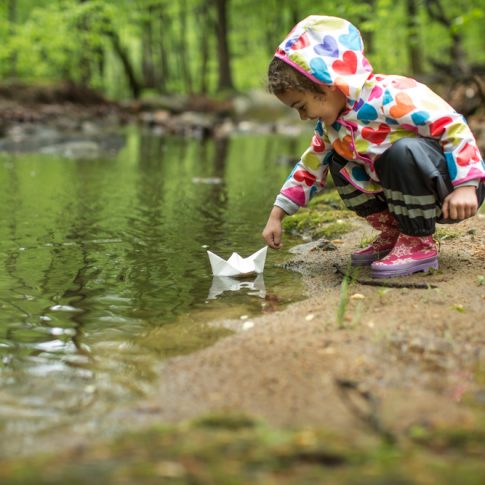 Little girl in the rain with her paper boat