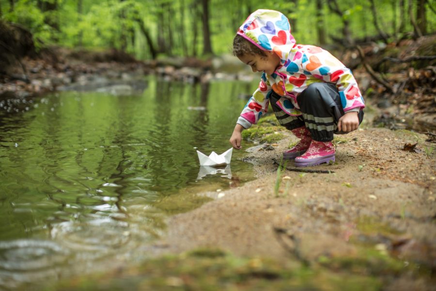 Little girl in the rain with her paper boat